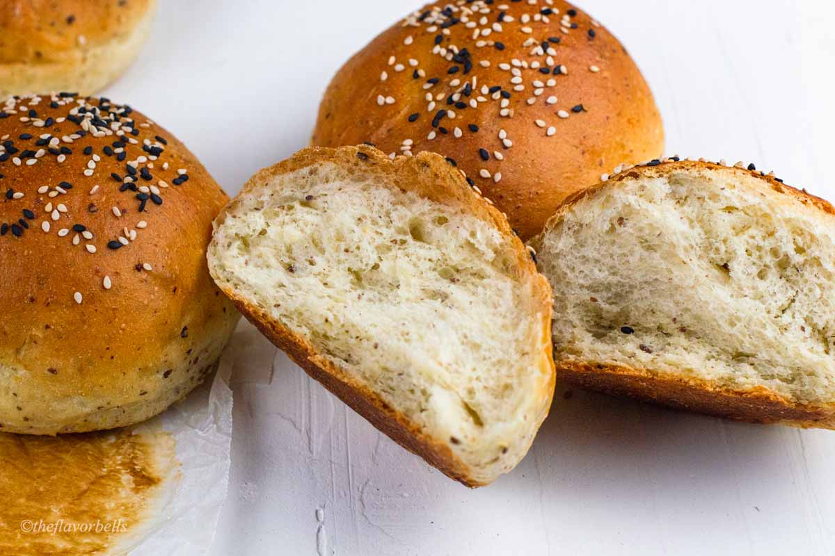 three vegan buns with one bun being broken to show the tender crumb