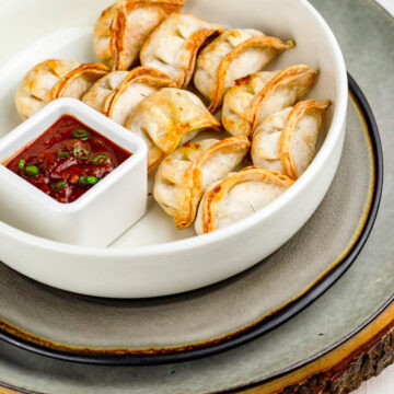 10 frozen potstickers made in air fryer served in a plate with sauces