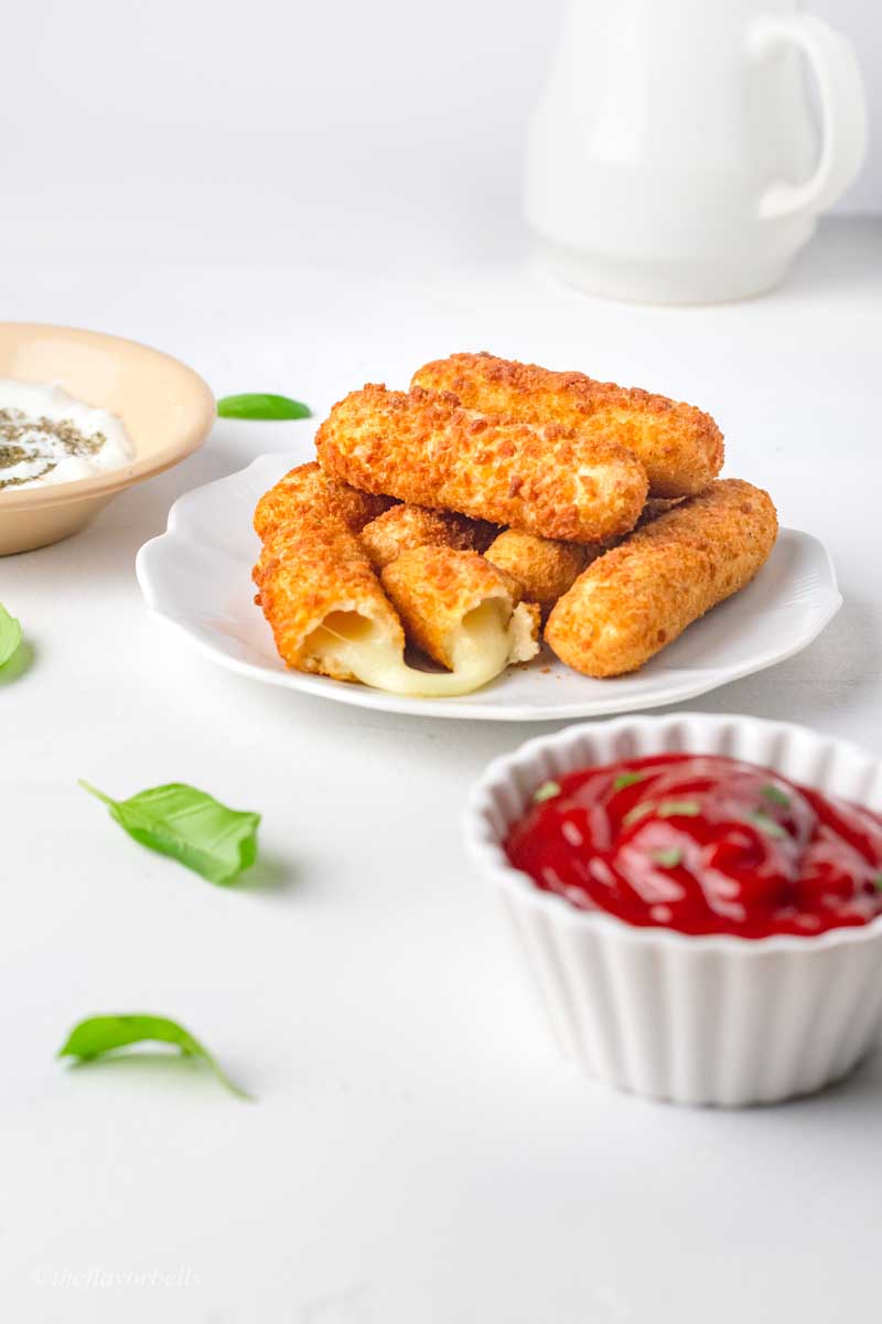 cheese sticks in plates served alongside dipping sauces