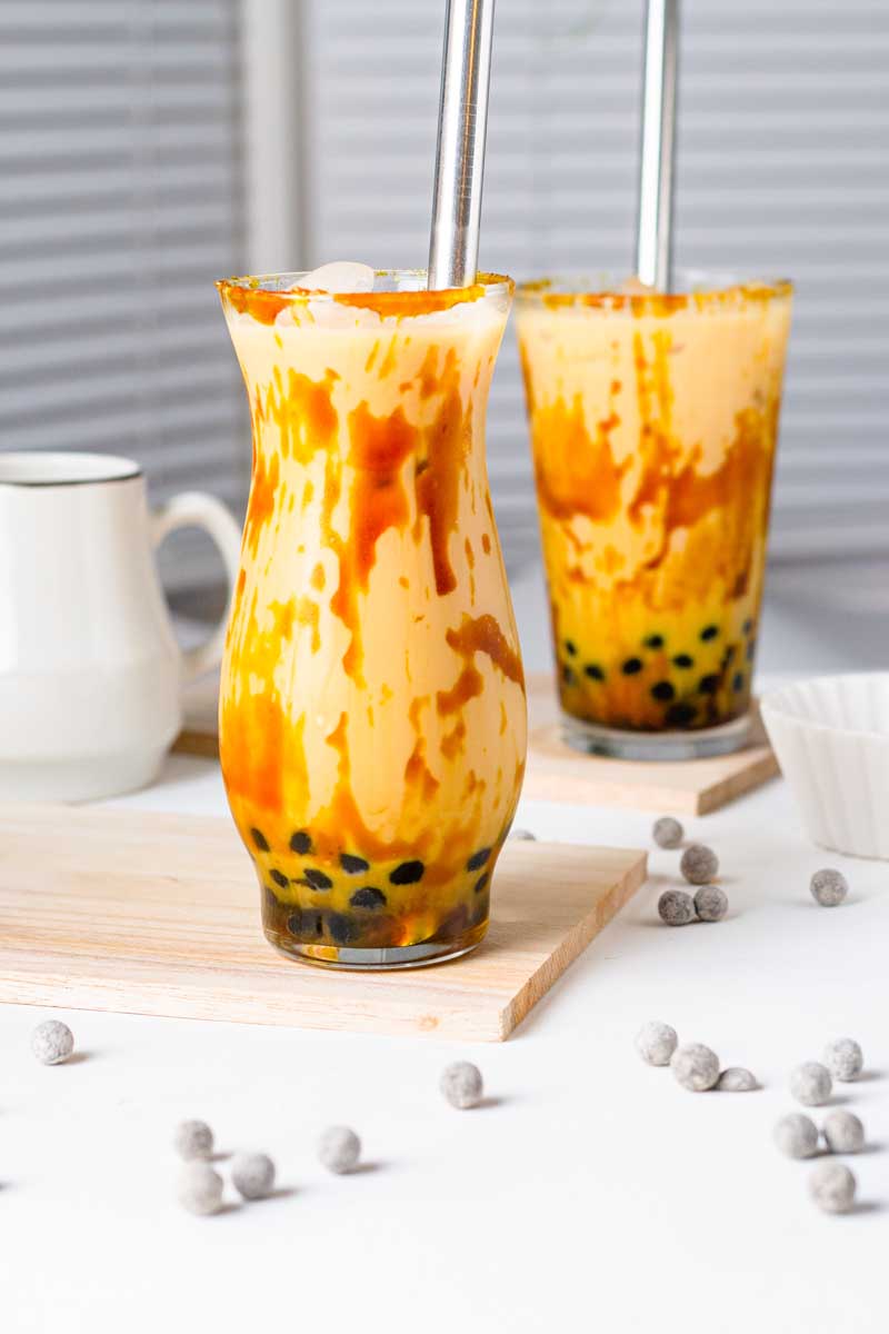 tiger boba tea in 2 glasses with black boba pearls spred on the table