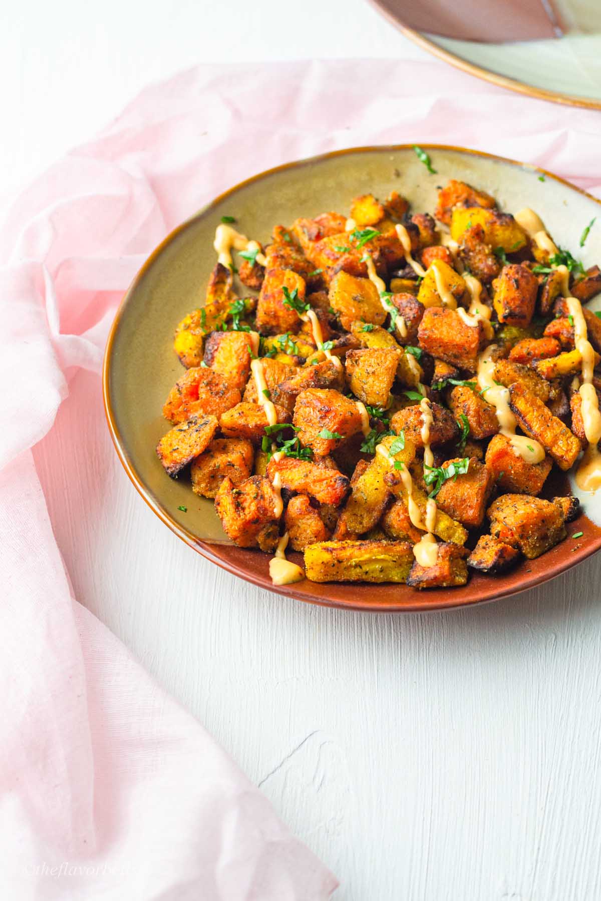 delicious looking plate of sweet potato chunks cooked with carrot chunks, spiced and coated in herbs