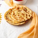three malabar parotha in a plate with visibly open flaky layers
