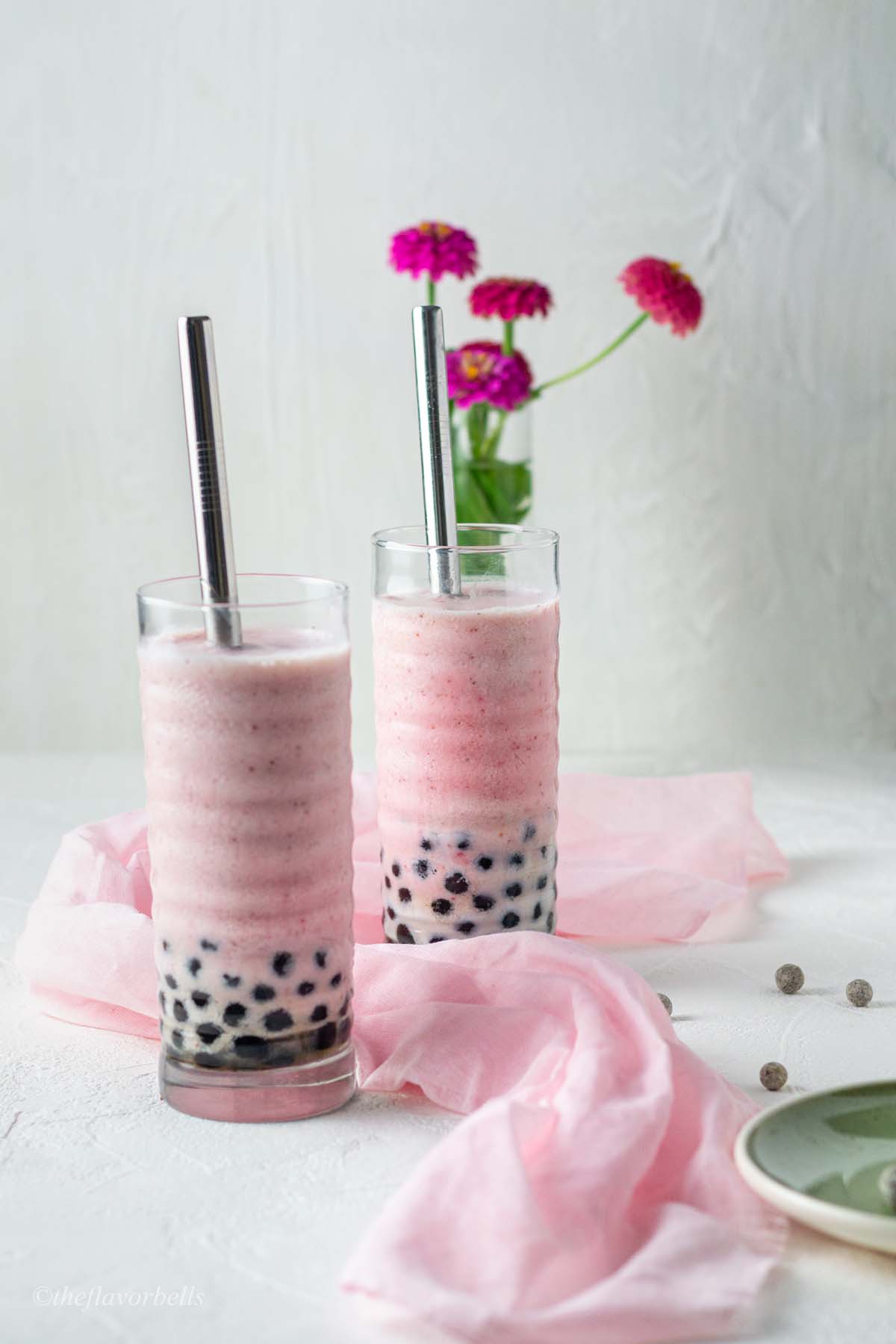 perfectly pink strawberry smoothy filled in curvy large glasses and at the base black tapioca pearls are showing themselves