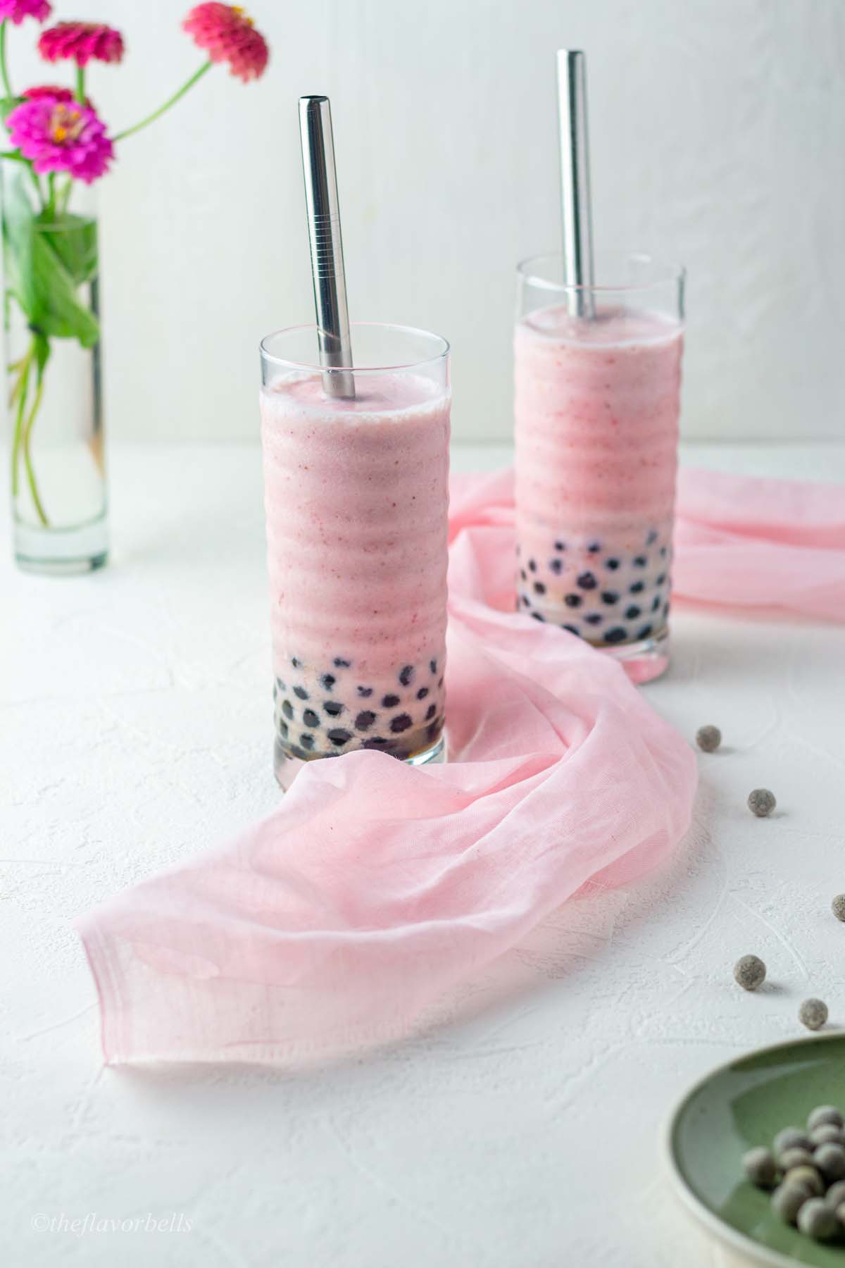 strawberry boba shake in 2 glasses and a pink cloth twirled around them
