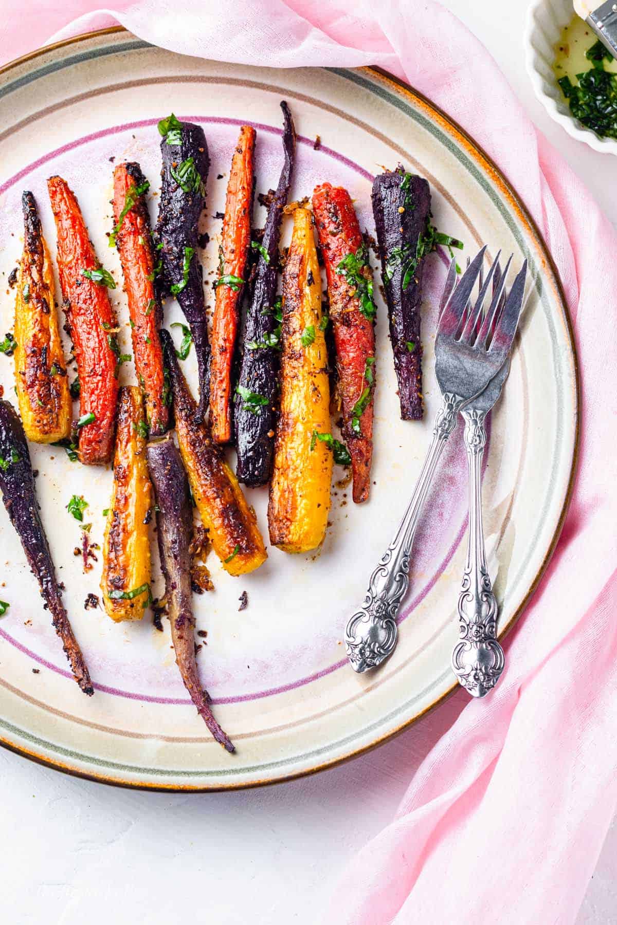 smoked rainbow carrots in a plate and garnished with green herbs
