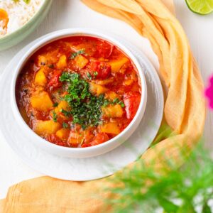 aloo and tamatar ki sabzi served with rise and topped with chopped cilantro