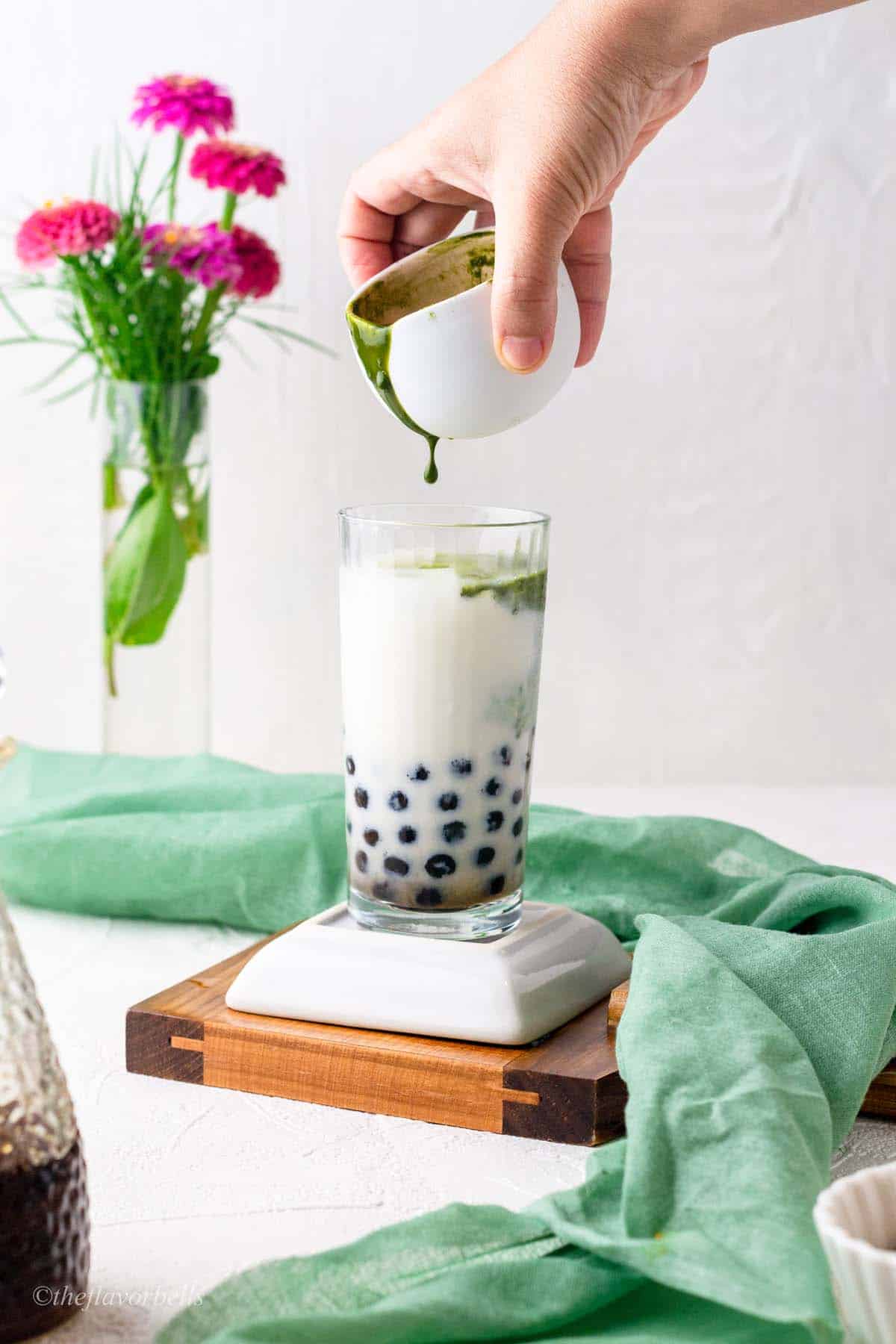 images showing adding green matcha to white milk bubble tea glass