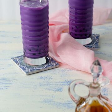 Two glasses of ube milk tea with a brown sugar syrup in the foreground
