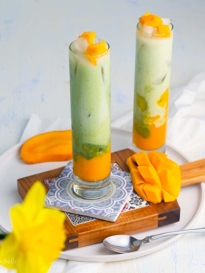 2 glasses of layered mango matcha topped with mango chunks