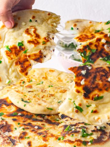 an images showing cheese filled naan topped with garlic butter