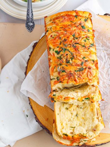 Pull apart bread that is topped with cheese and filled with cheese and baked garlic butter