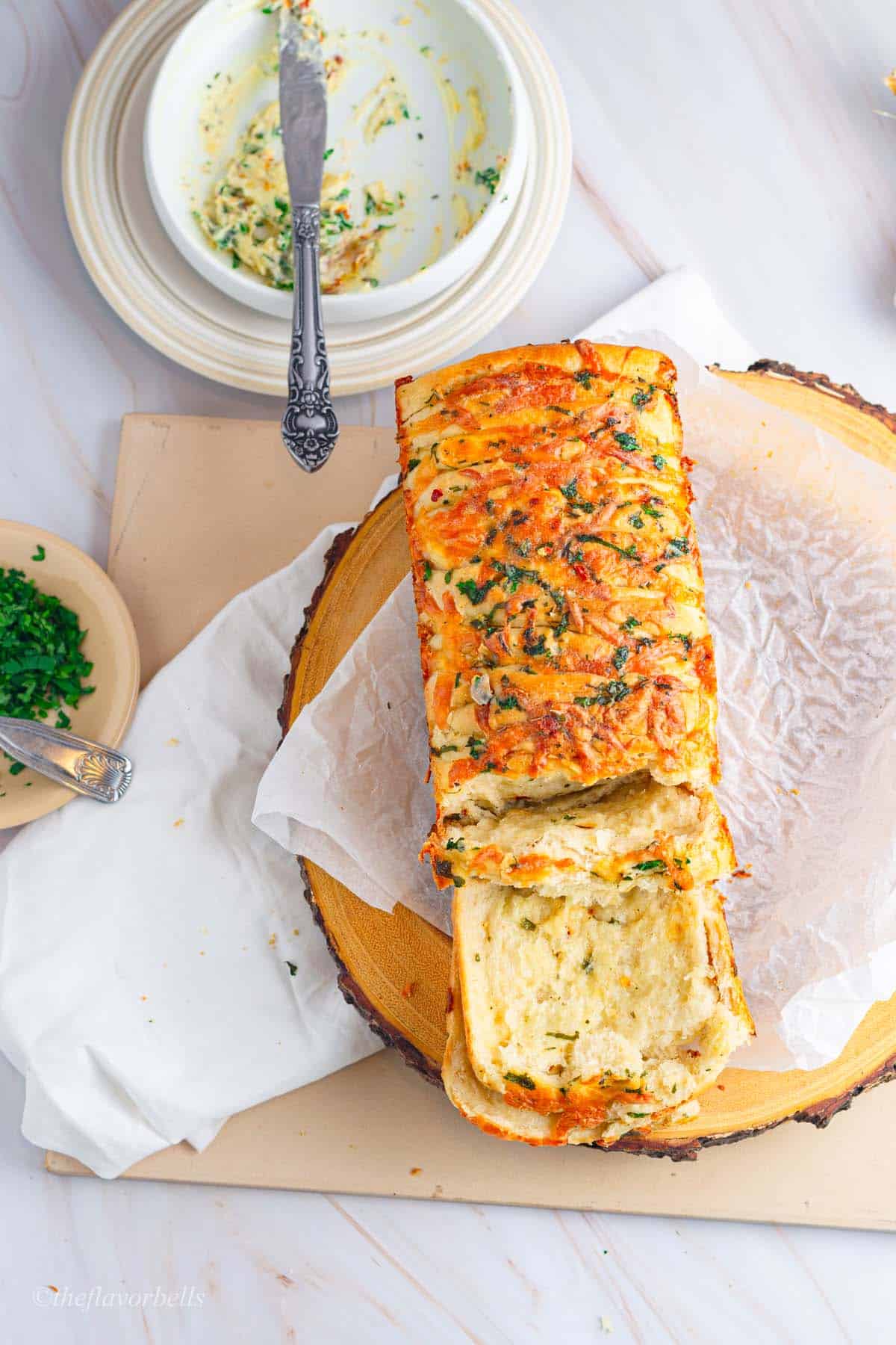 an overhead shot 
 of cheesy garlic pull apart bread loaf made at home from scratch and topped with herbs