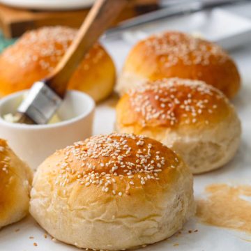 potato hamburger buns placed on a parchment paper and a butter brush on the side