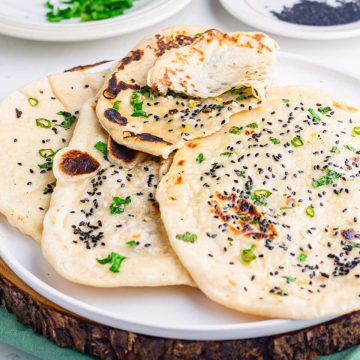 Stack of homemade Bullet Naan infused with garlic , nigella seeds, and green chilies. This spicy naan pairs well with rich Indian gravies and chutneys.