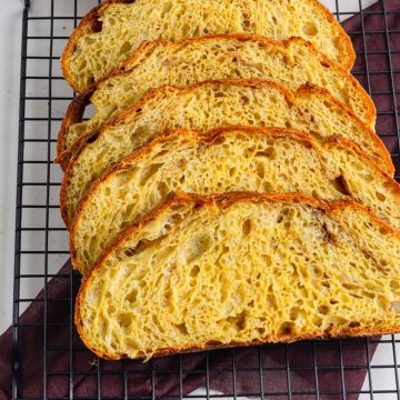 Homemade pumpkin sourdough loaf cooling on a wire rack, highlighting its crisp crust and rustic appearance.
