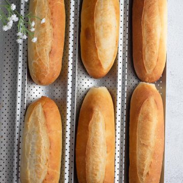 Close-up of freshly baked Bánh Mì rolls with a golden, crunchy crust and light, fluffy texture.