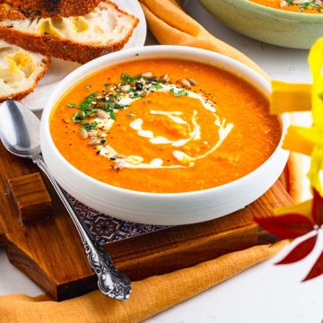 two bowls filled with ginger carrot lentil soup with sourdough bread served on the side