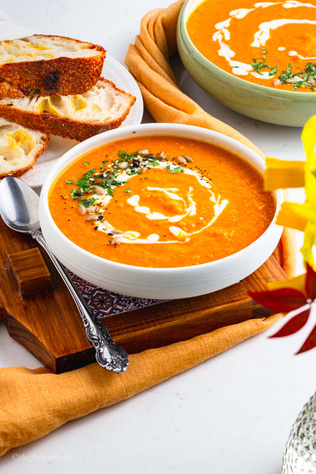 two bowls filled with ginger carrot lentil soup with sourdough bread served on the side
