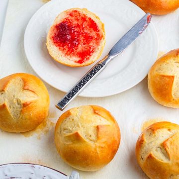 one bun sliced and smeared with strawberry jam and 6 more danish buns around it
