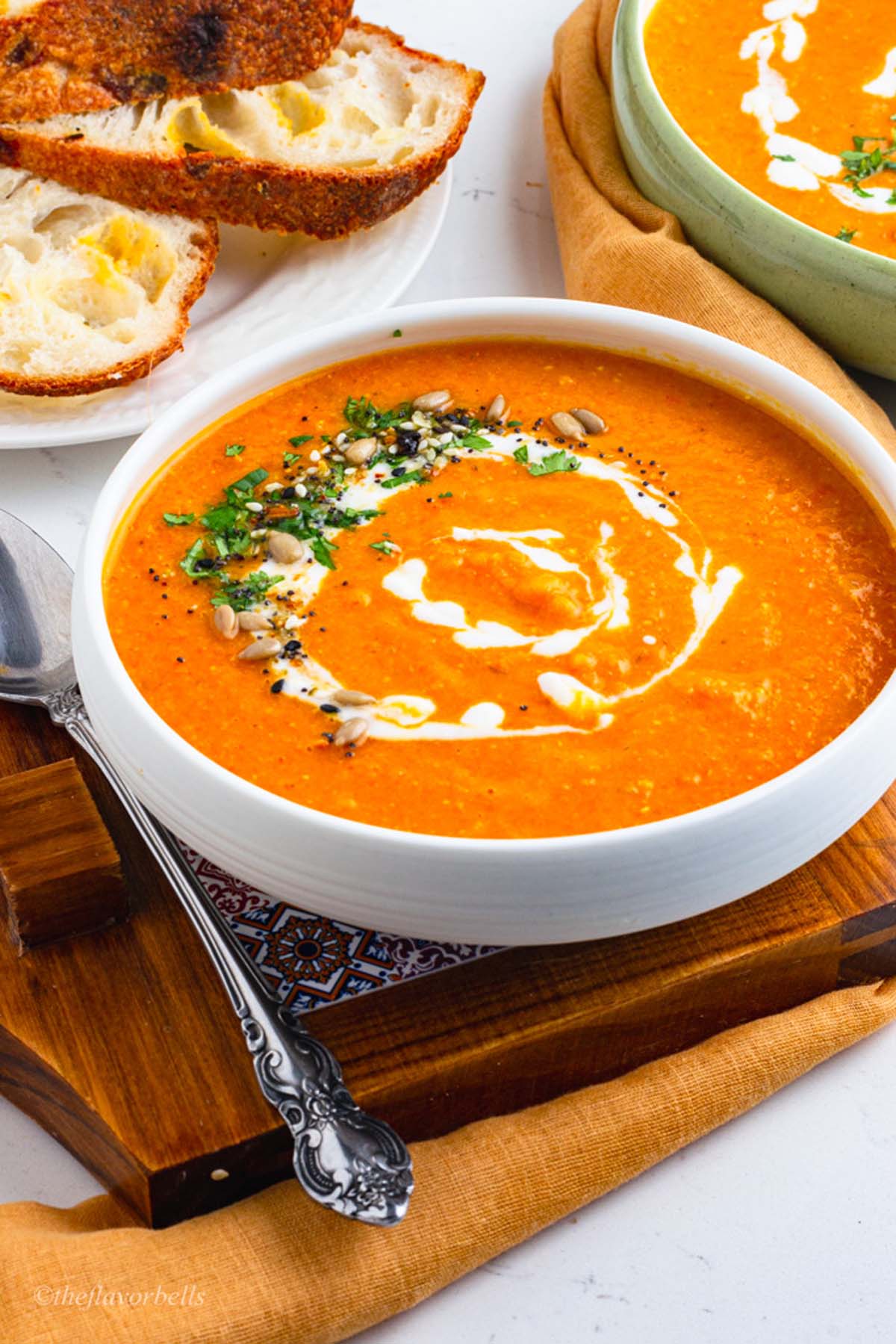 smooth and creamy carrot lentil soup served in bowls and beautifully garnished with cream, herbs, seeds and nuts
