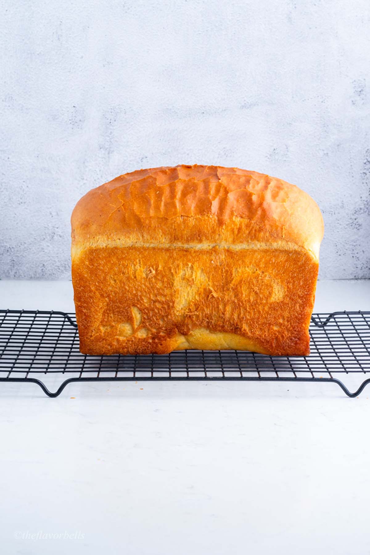 a freshly baked sandwich bread loaf cooling on a wire rack