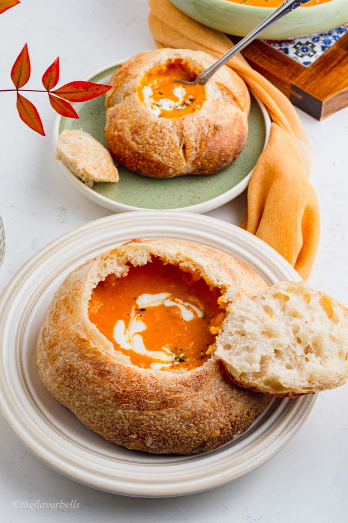 two sourdough bread bowl filled with warm and filling soup and topped with cream and nuts