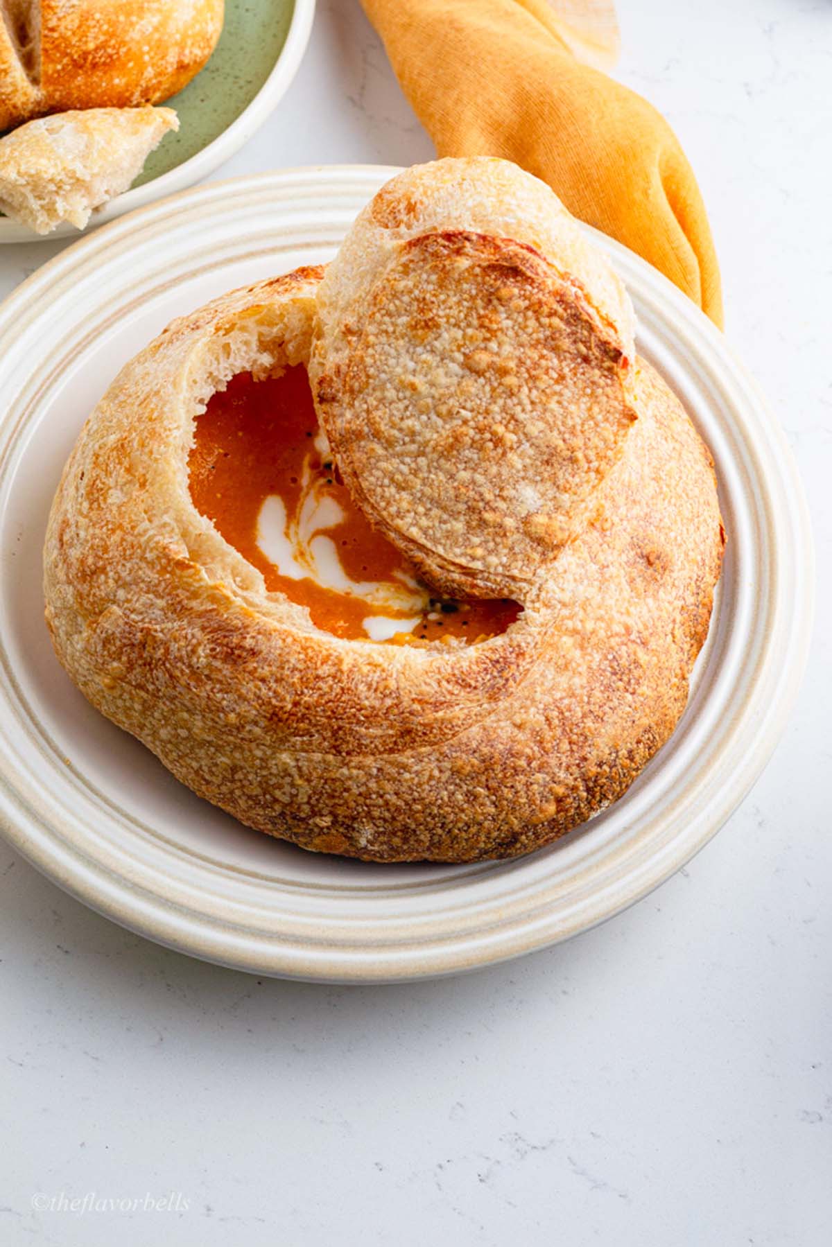 a sourdough bread bowl with a bread lid with soup inside it.