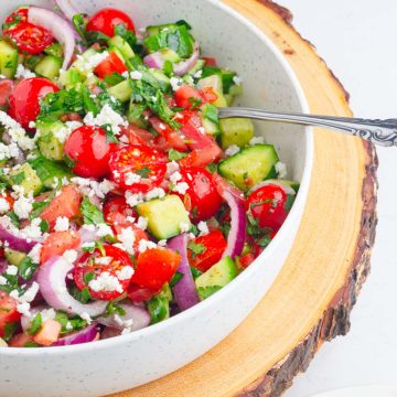 a bowl filled with refreshing and colorful mediterranean cucumber and tomato salad