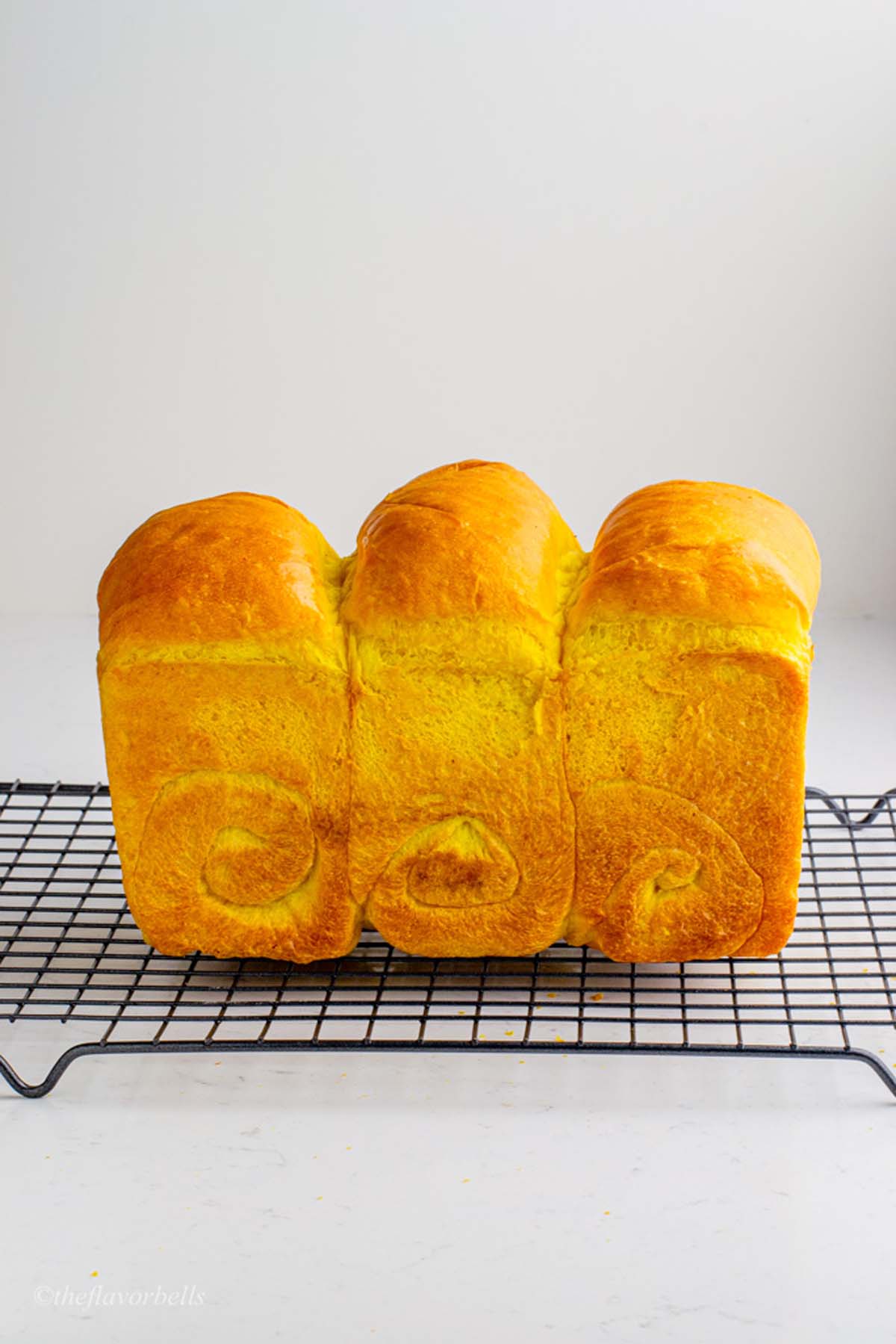freshly baked turmeric bread cooling on a wire rack, brushed with butter to give it a glossy and soft crust