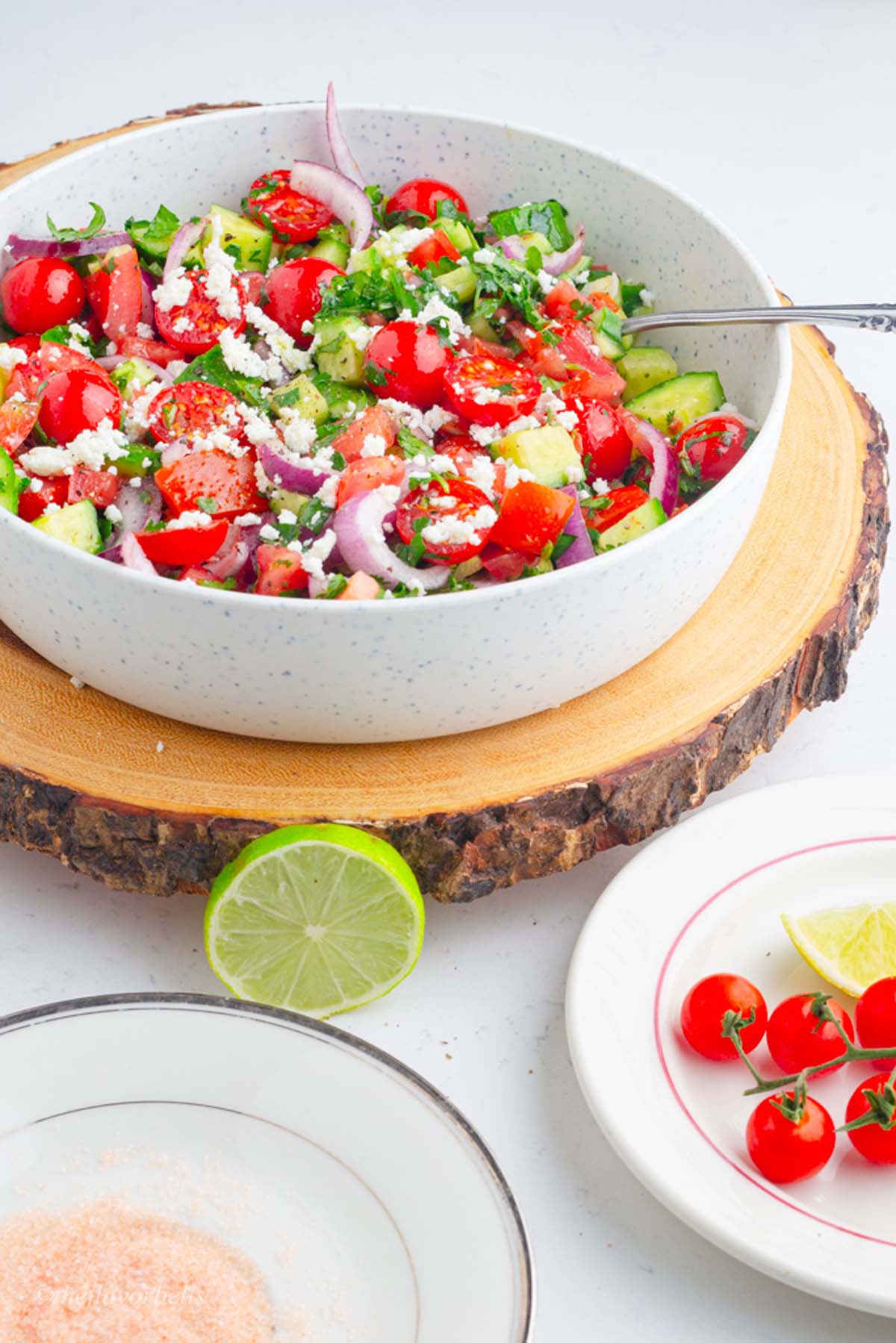 cucumber and tomato salad in the background with lime  and a salt saucer in the foreground