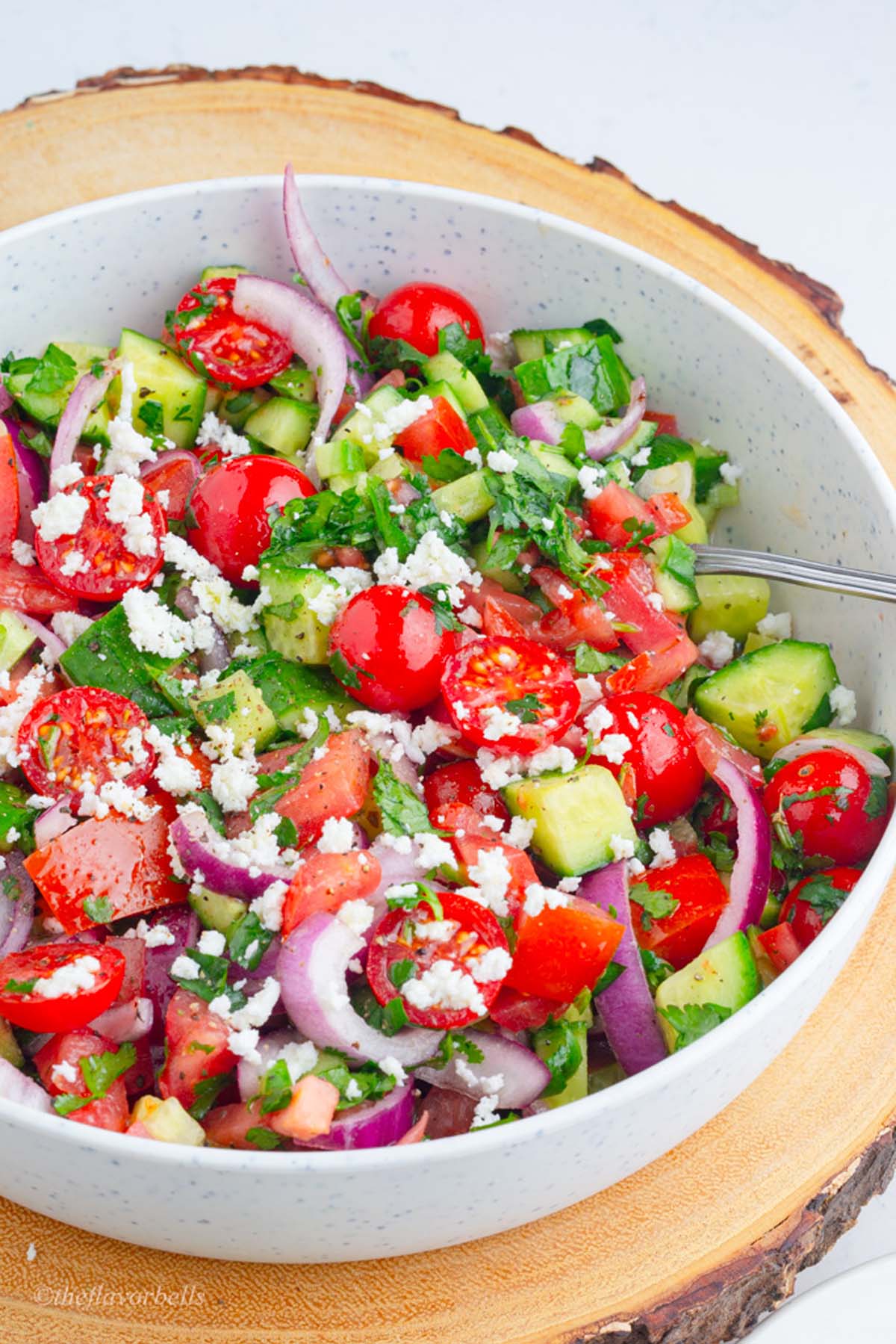 a spoon filled with zesty mediterranean tomato and cucumber salad 