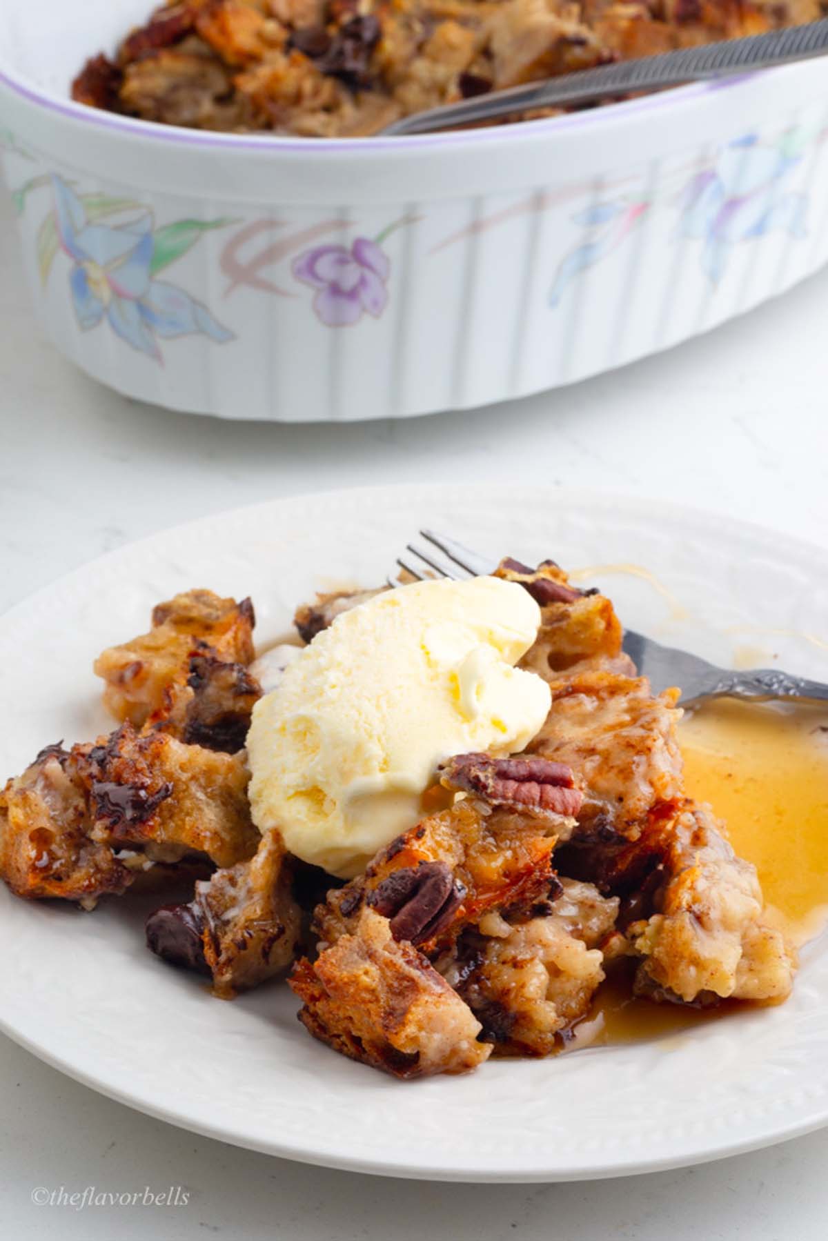 a plate with the pudding served with maple syrup and vanilla ice cream