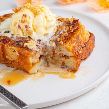 a close up shot at the custardy on the inside and crunchy on the outside french toast topped with a scoop of ice cream