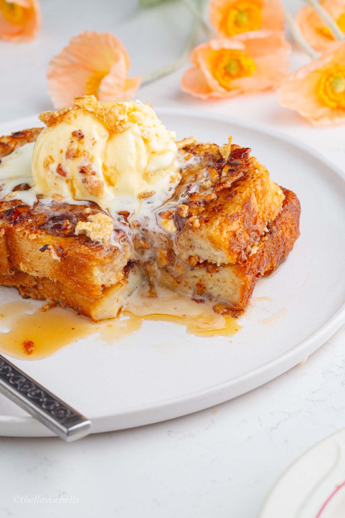 a close up shot at the custardy on the inside and crunchy on the outside french toast topped with a scoop of ice cream