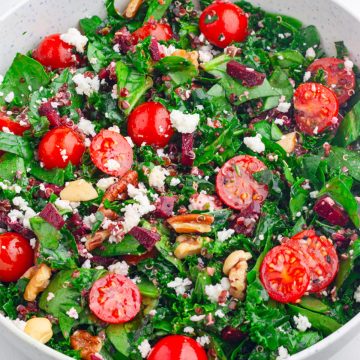 a close up look at the kale spinach salad with red quinoa, which is topped with crumbled feta and chopped nuts