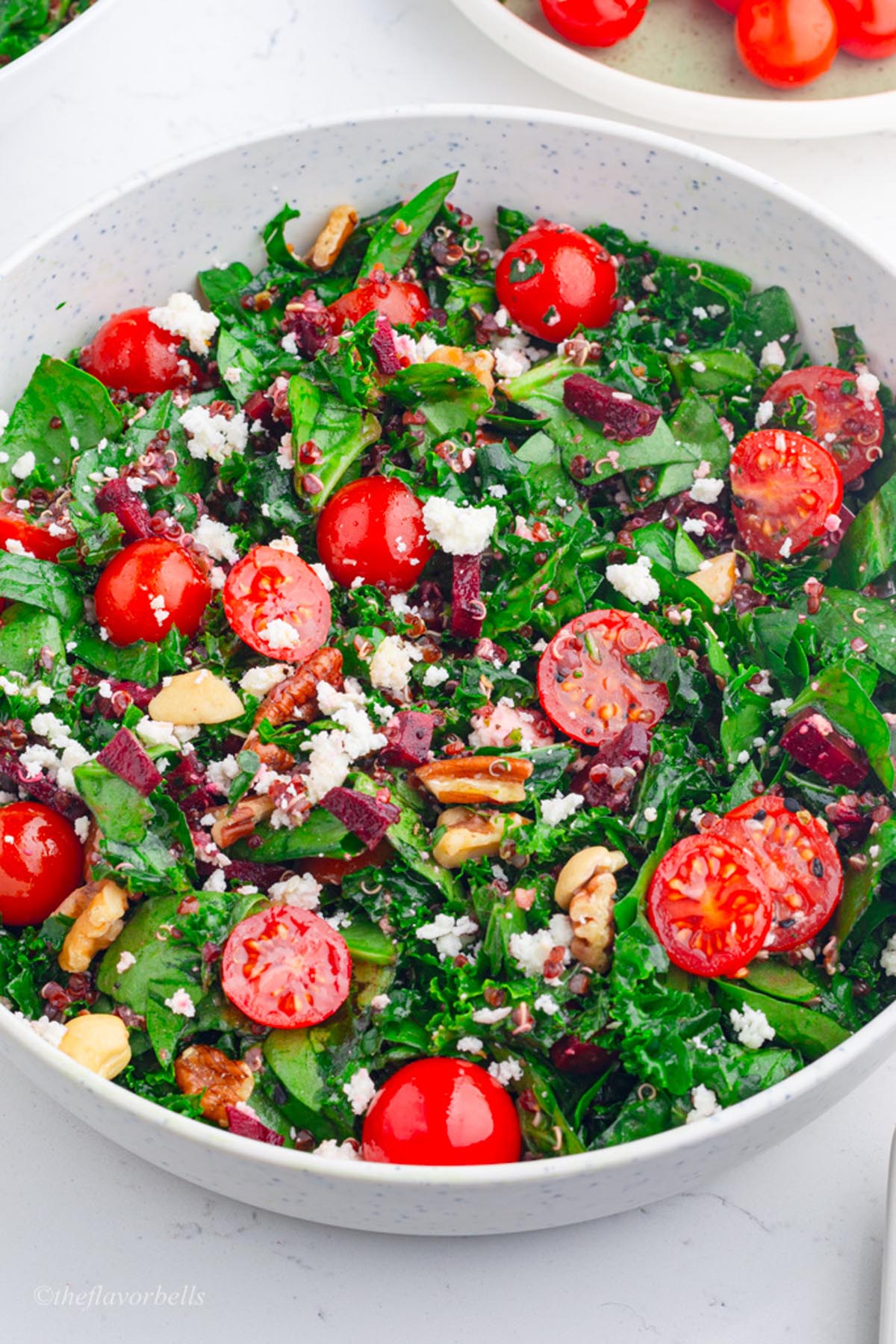 a close up look at the kale spinach salad with red quinoa, which is topped with crumbled feta and chopped nuts