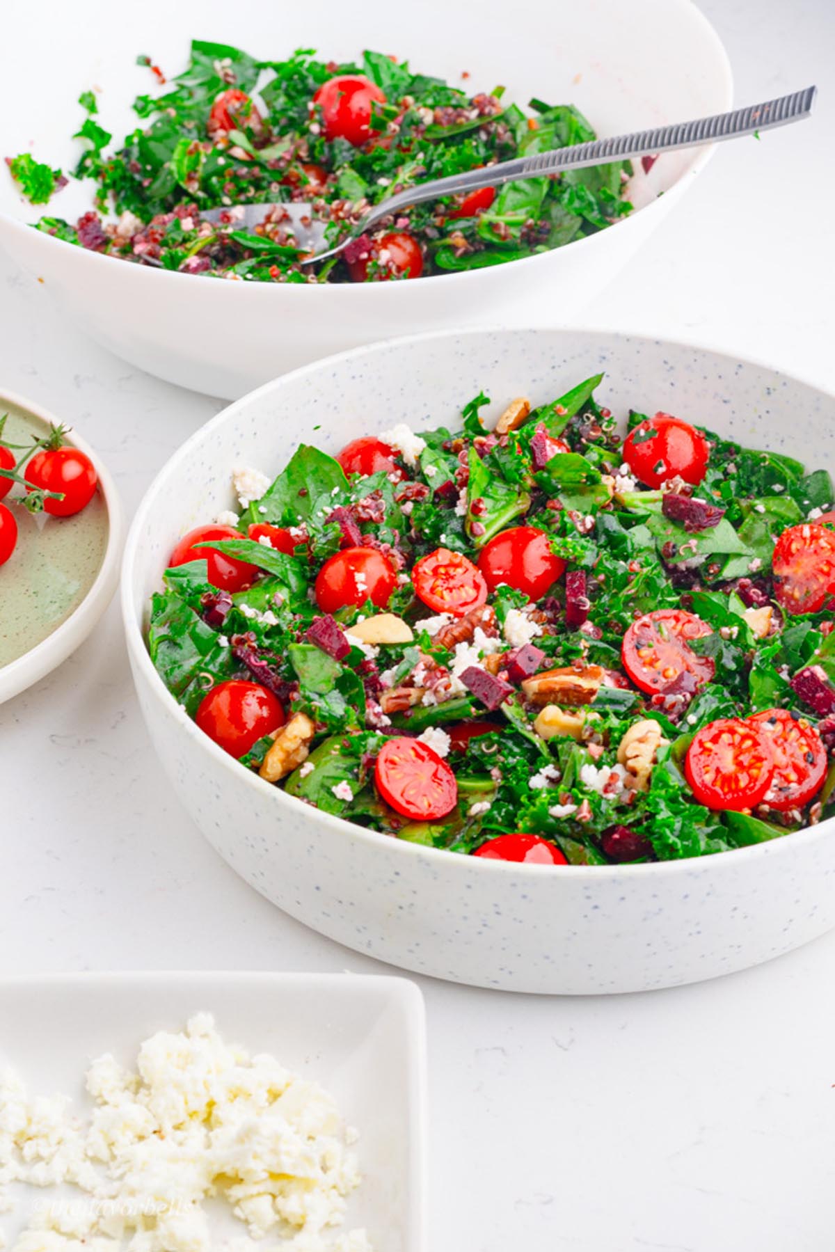 two bowls of the green leafy salad with quinoa and cheery tomatoes kale and spinach. 