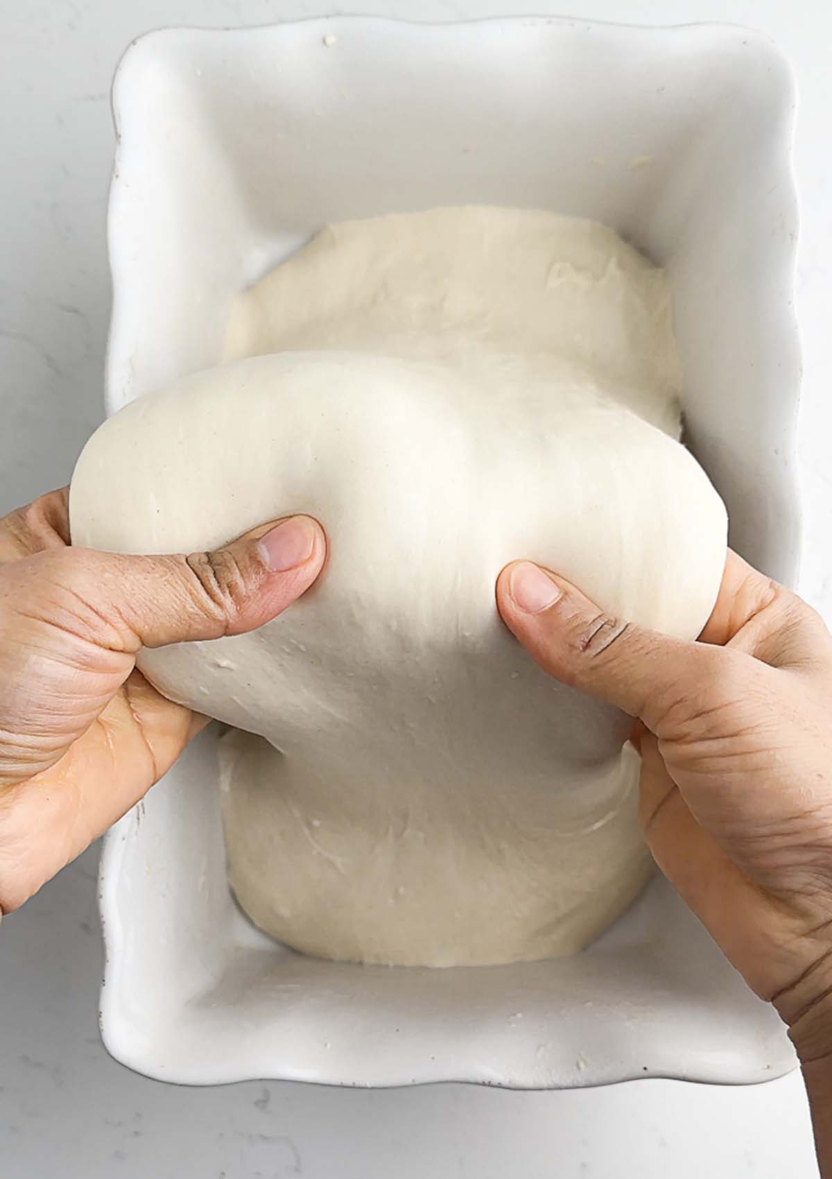 an image showing the baker conducting coil fold on a dough