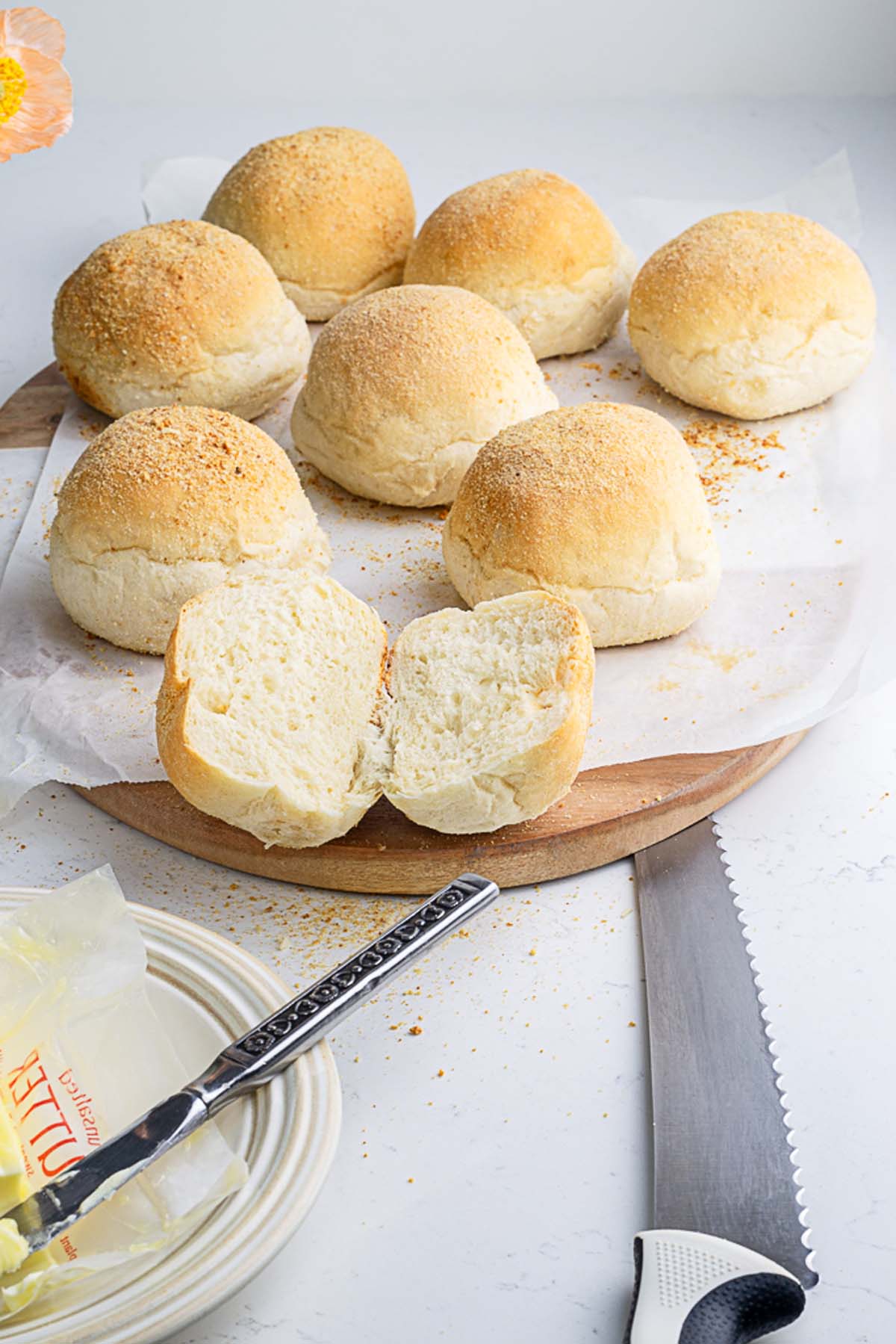 7 soft and fluffy pandesal made without eggs in the background and one sliced buns in the foreground