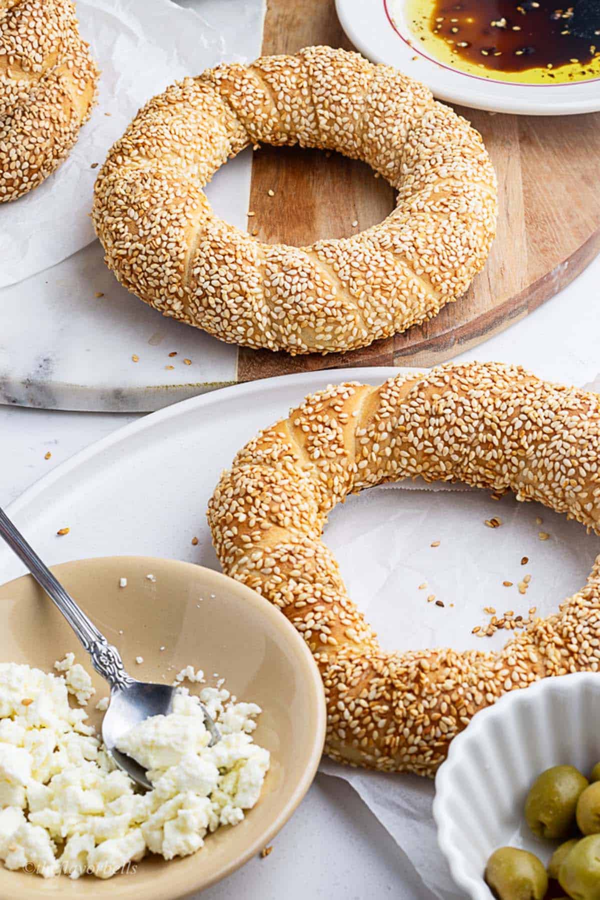 two simit on the serving board served with olive oil and balsamic vinegar, olives and feta cheese