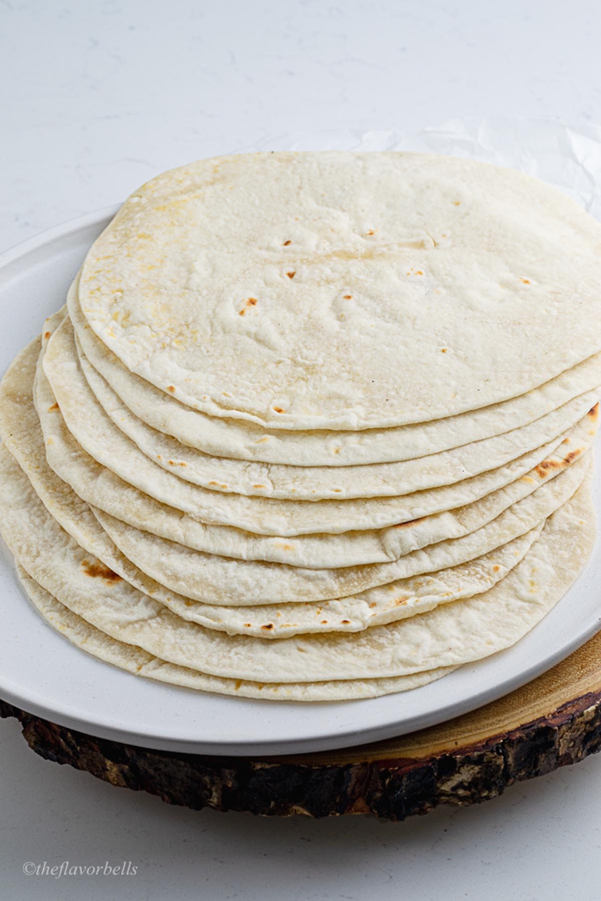 a stack of freshly made sourdough tortillas in a white plate