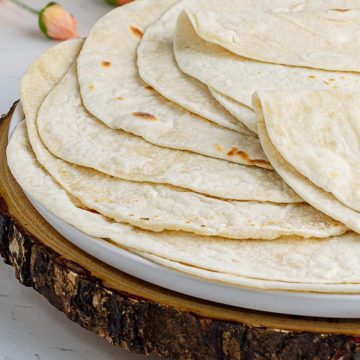 a close up shot at the flour tortillas made up of sourdough discard showing off thin and even perfectly round tortillas