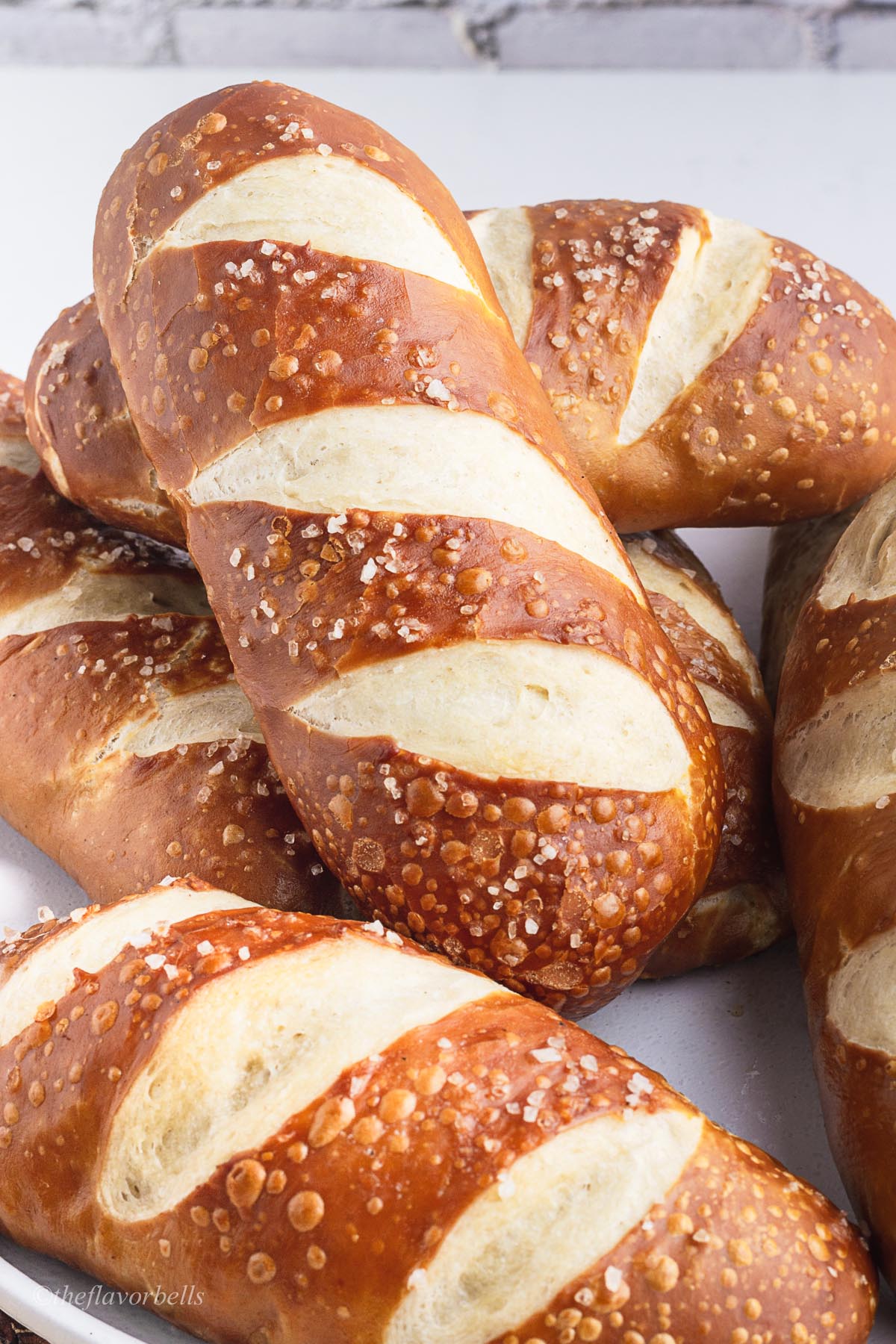 a close up shot at the pretzel hot dog buns topped with coarse sea salt.