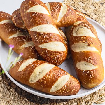 6 shiny and chewy pretzel hot dog buns placed in a white plate