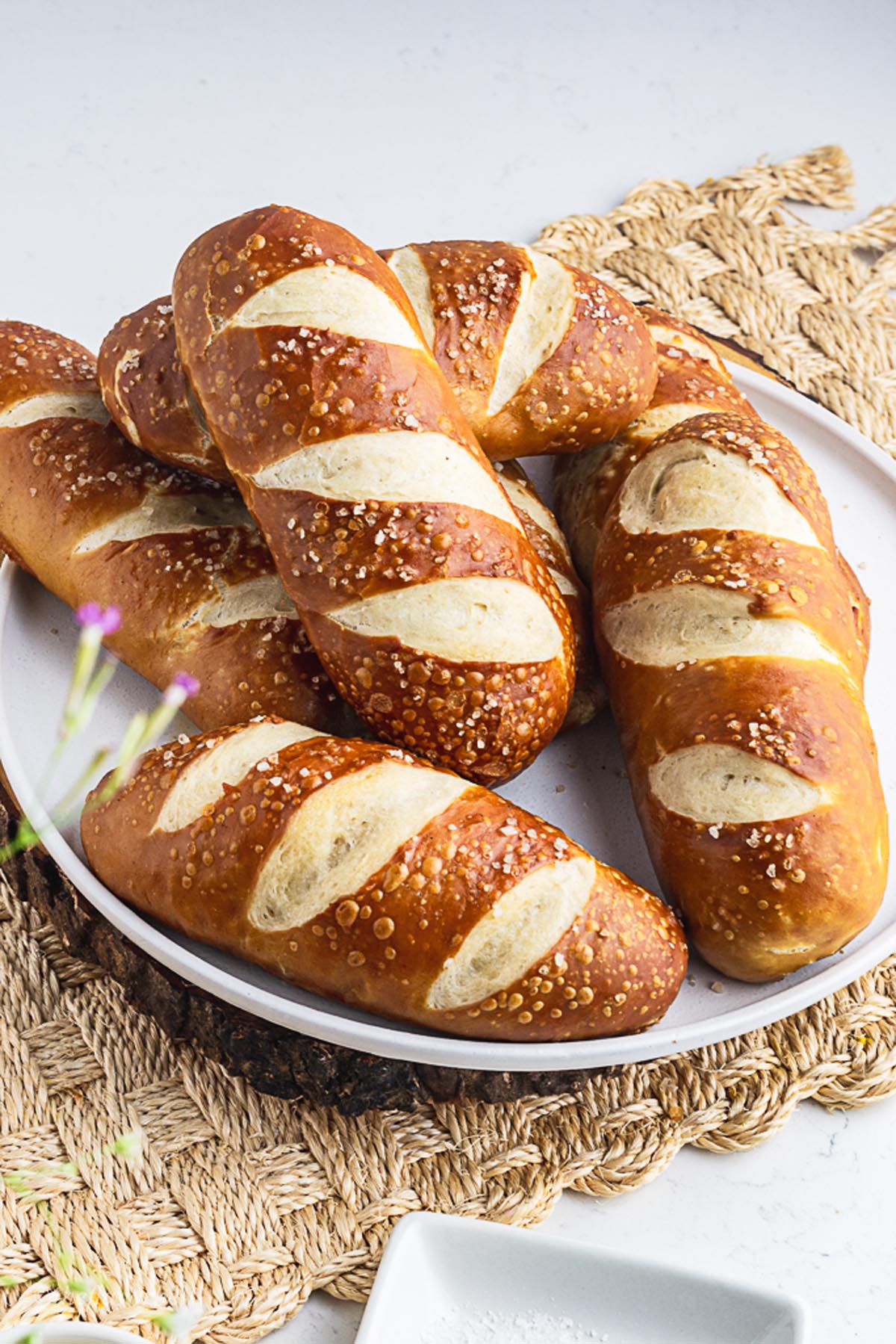 6 shiny and chewy pretzel hot dog buns placed in a white plate